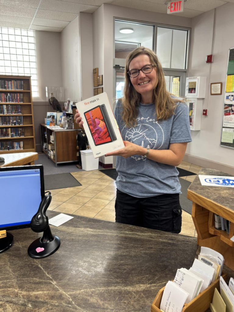 A woman smiling, holding a new tablet, still in the box